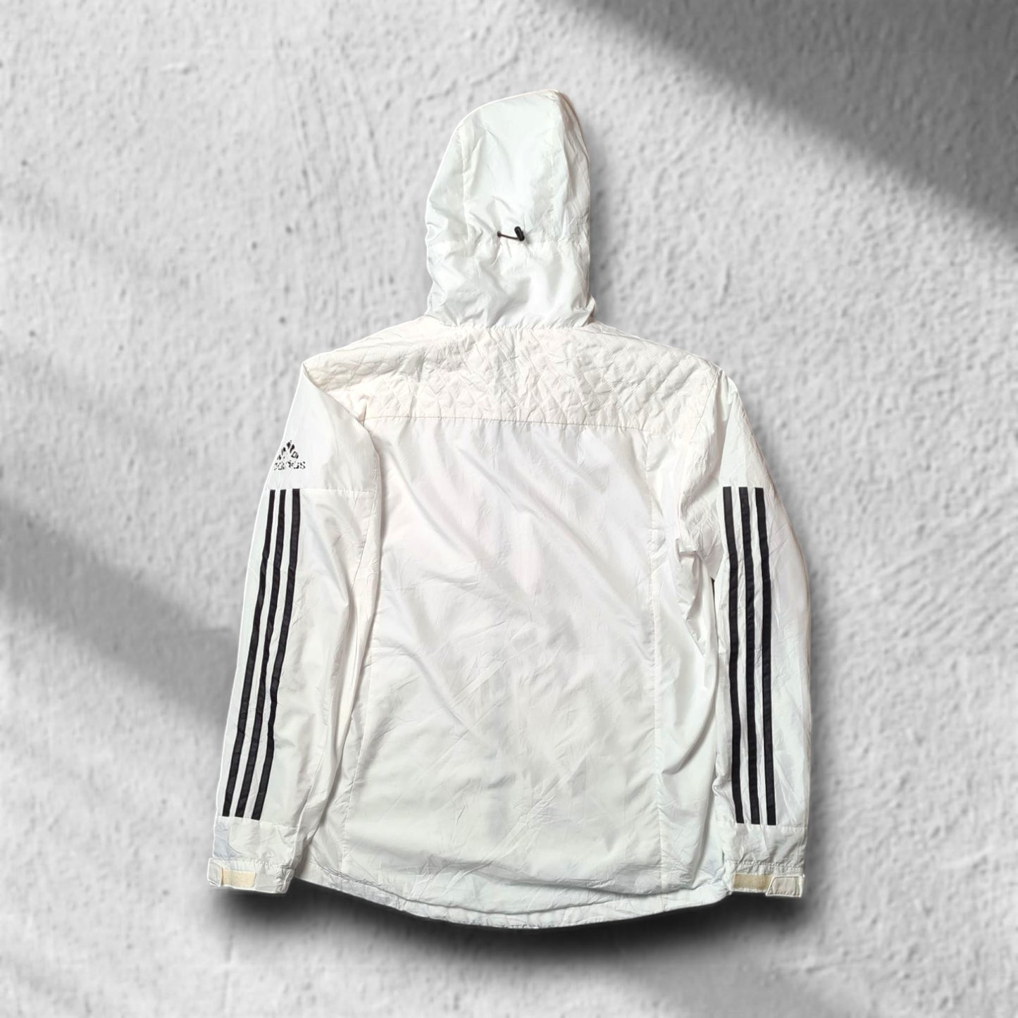 Schlichter Rückenansicht des weißen adidas Windbreakers mit Kapuze und leichtem Oversized-Schnitt