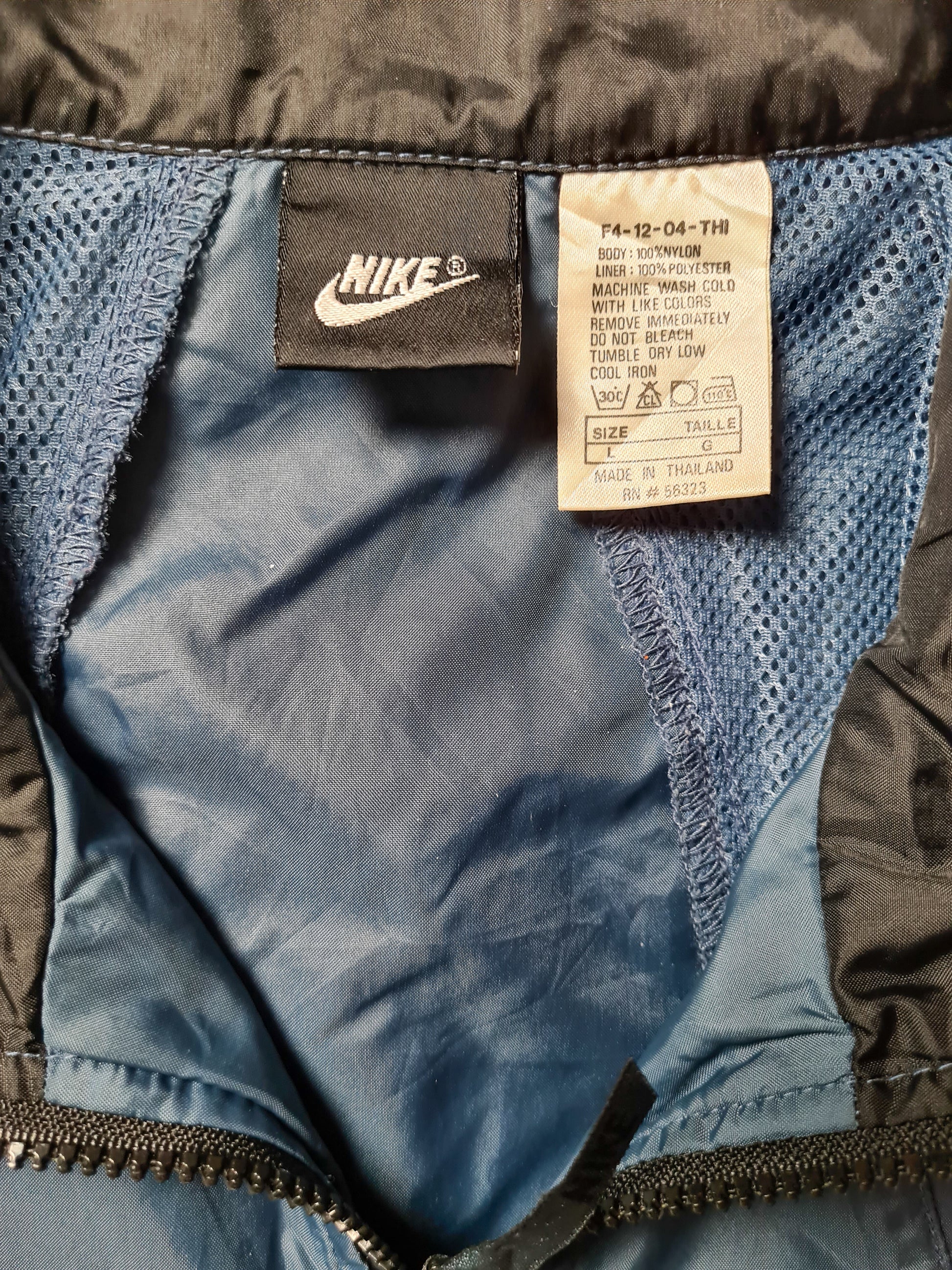 Innenetikett mit Nike-Logo und Pflegehinweisen des Windbreakers (Größe L, Made in Thailand).