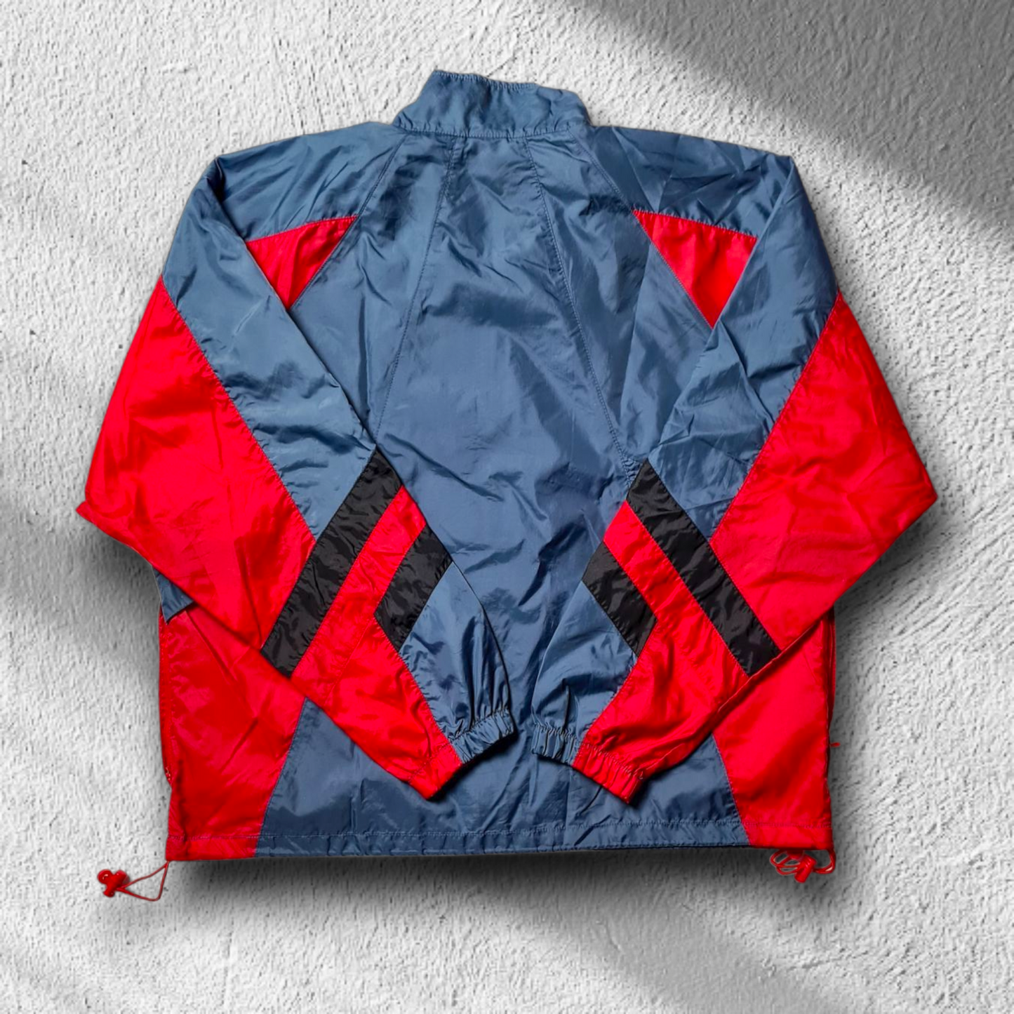 Rückseite des Nike Windbreakers mit rot-blauen Colorblock-Elementen.