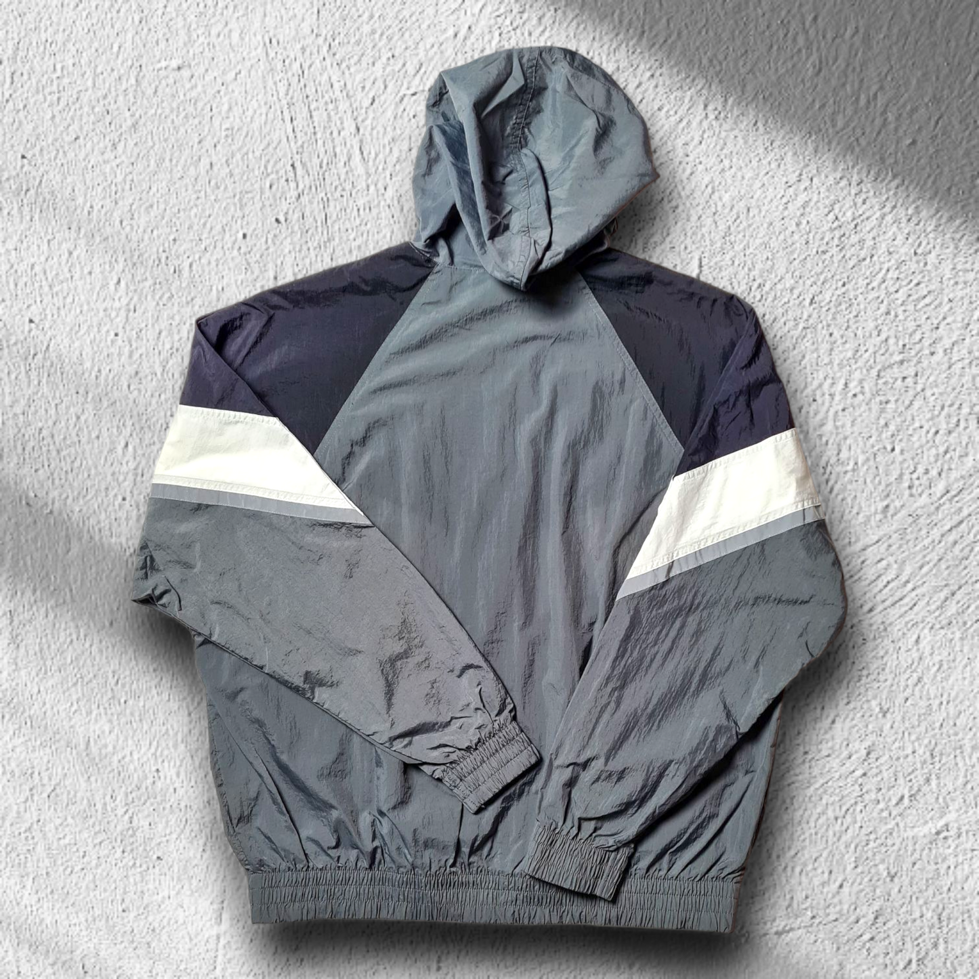 Rückansicht des grauen Nike Windbreakers mit Chevron-Design