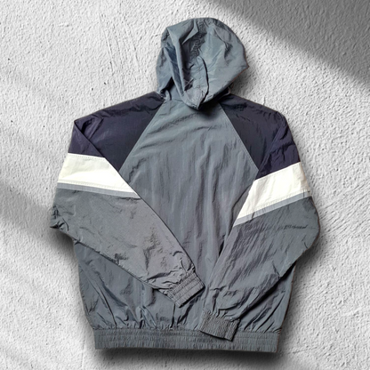 Rückansicht des grauen Nike Windbreakers mit Chevron-Design