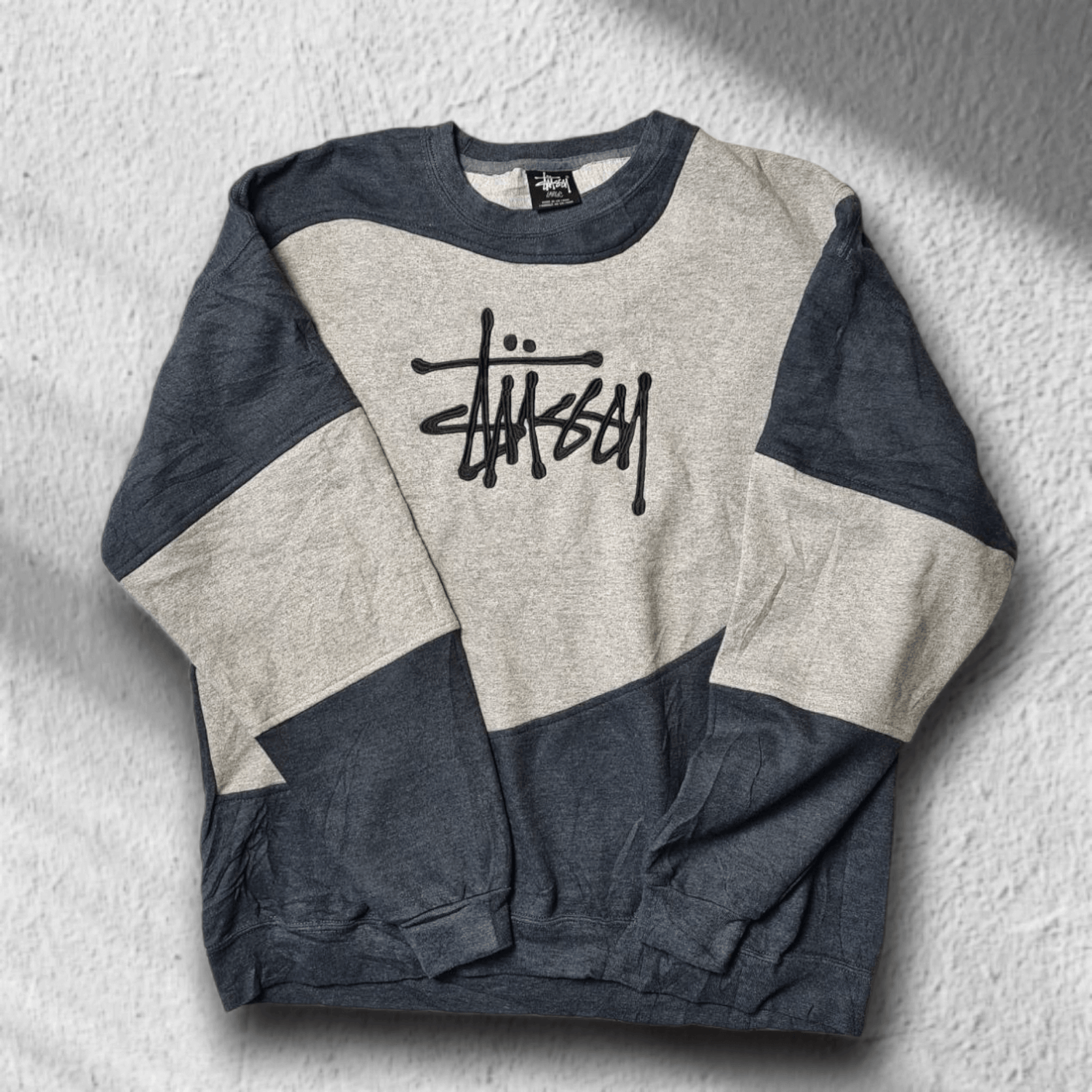 Vorderseite des zweifarbigen Stüssy Rework Sweaters in L mit gesticktem Logo