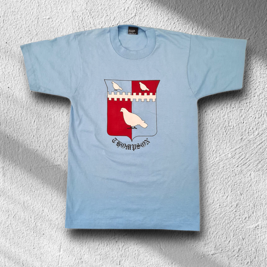 Vorderseite des blauen Screen Stars Best T-Shirts mit auffälligem Thompson-Wappenprint, flach liegend.